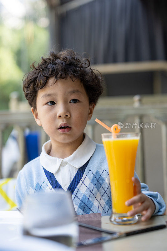 在餐馆里喝果汁的小男孩