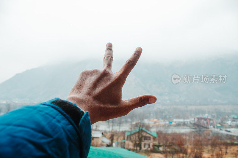 在印度喜马恰尔邦的马纳里，一名印度男子在山前做和平的手势