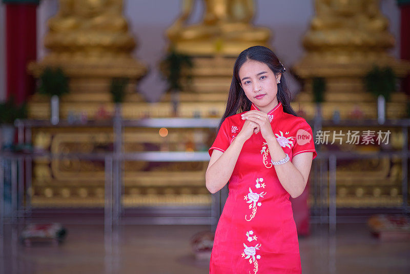 亚洲妇女在传统的红色服装敬礼