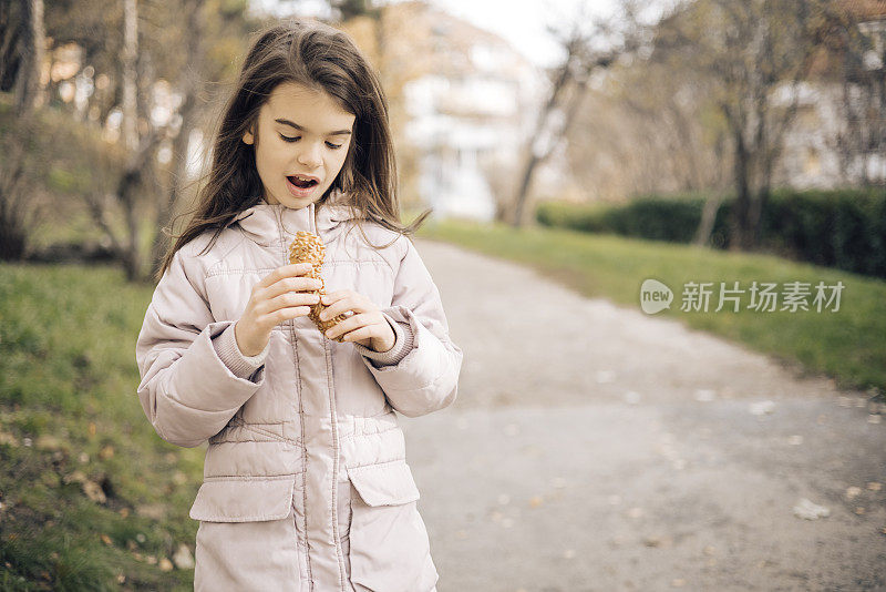 一个小女孩在公园里吃点心的照片
