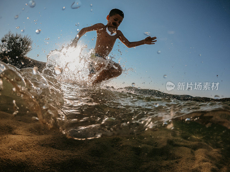 小男孩在沙滩上玩水玩得很开心