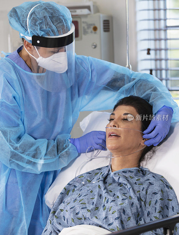 穿着个人防护装备的护士给病床上的病人供氧