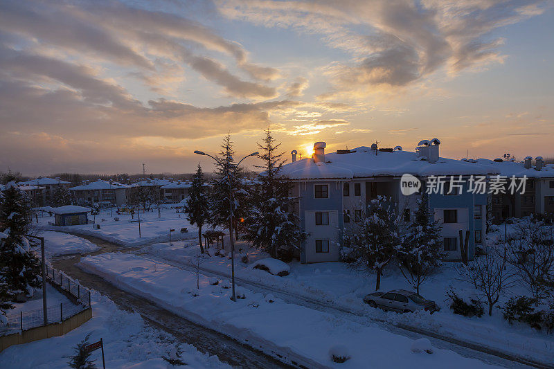 在一个下雪的冬日，夕阳和房子。