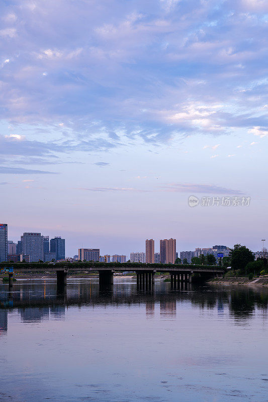 阳光明媚的日子里，沿河有现代化的建筑和桥梁