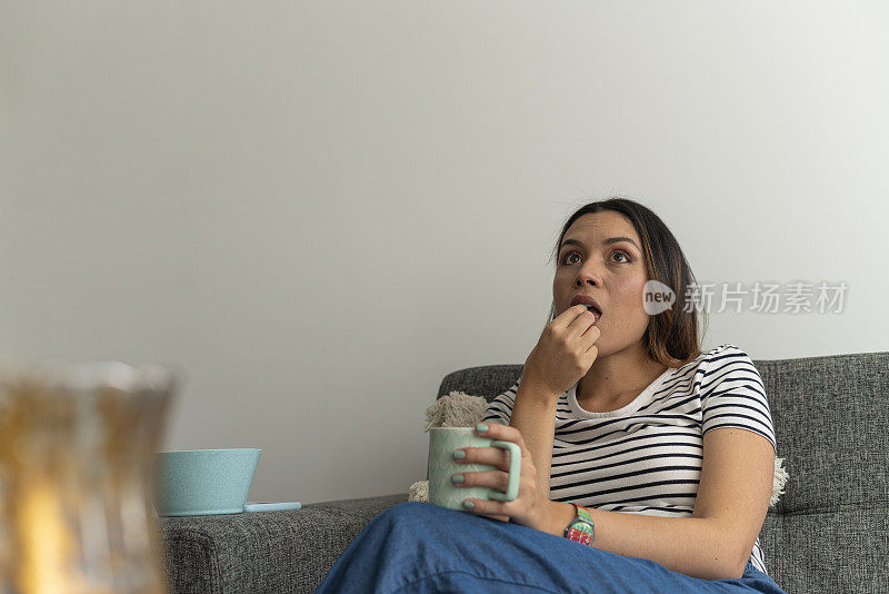 一位拉丁妇女在舒适的家里聚精会神地看电视连续剧