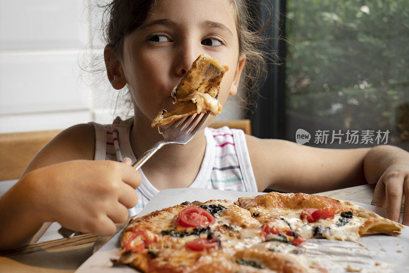 一个小女孩拿着一块美味的披萨