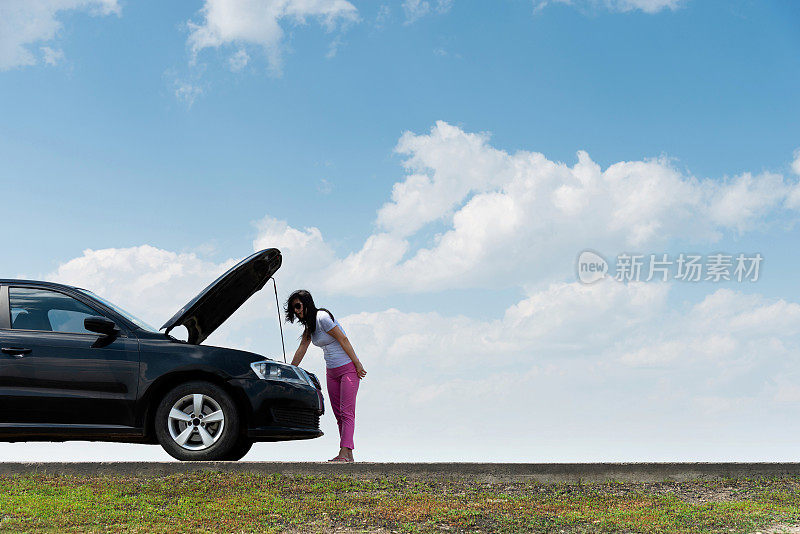 女人试图修理坏了的汽车