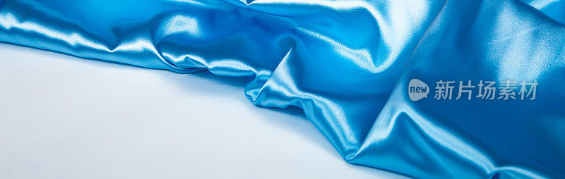 光滑优雅的波浪粉彩浅蓝色缎面丝绸奢华布面料纹理，抽象的背景。横幅