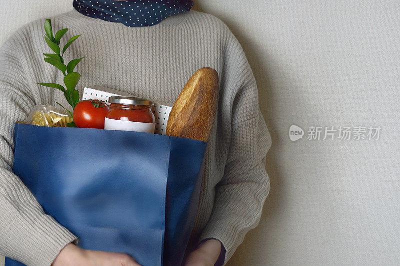 女人拿着装满食物的杂货袋