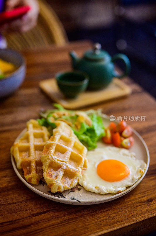 早餐有芝士华夫饼、煎蛋、番茄、鹰嘴豆泥和芝麻菜