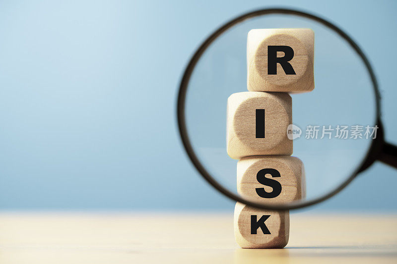 风险用语印屏于木块立方体和聚焦放大镜上，用于金融银行风险分析与管理，风险与回报的概念。