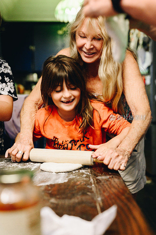 奶奶和孙女在室内用擀面杖一起烘焙，在家里开心地做饭，增进感情
