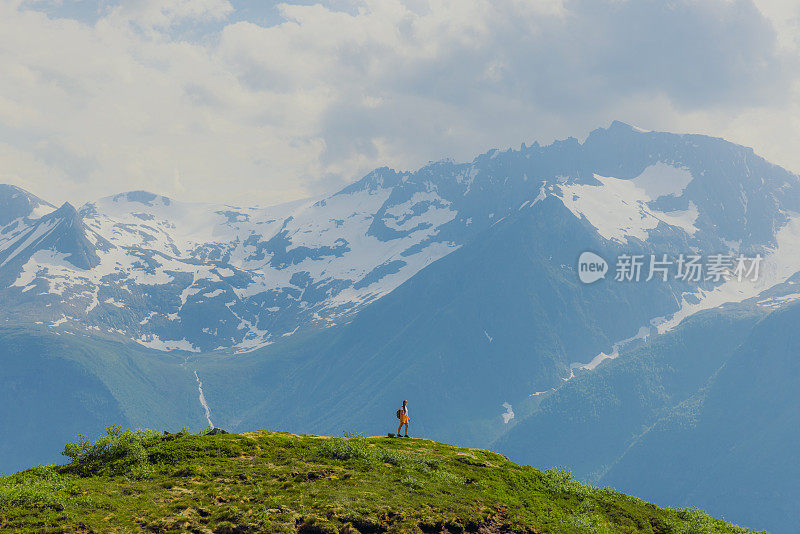 女子在远距离徒步旅行与背景风景秀丽的森莫尔阿尔卑斯山在挪威