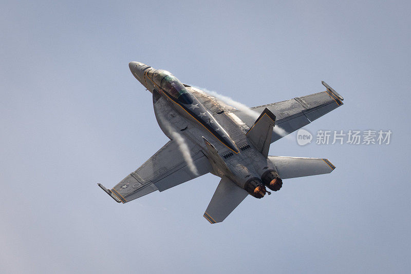 F-18大黄蜂高G机动的非常近的俯视图，在美丽的光线下，机翼根部有凝结条纹