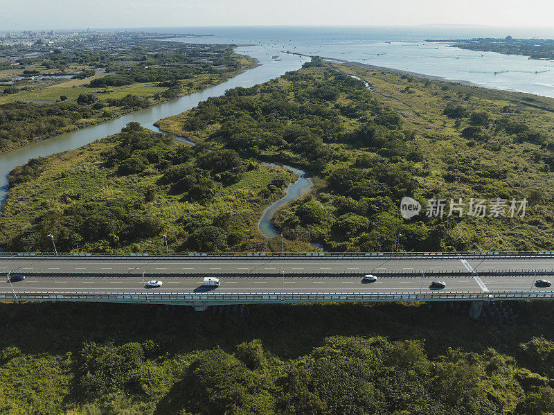 汽车在高速公路路口行驶的鸟瞰图。桥梁道路与绿色花园和树木相连接的建筑概念。