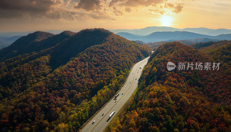 通往北卡罗来纳州阿什维尔的I-40高速公路穿过阿巴拉契亚山口，沿途有黄色的秋天森林和快速行驶的卡车和汽车。高速州际交通的概念