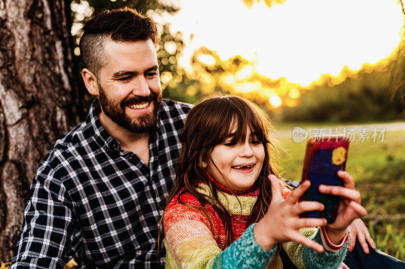 秋天，父亲和上小学的女儿用手机自拍，享受户外大自然的时光