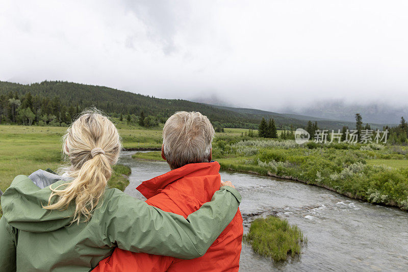 老年远足夫妇停下来欣赏风景，下雨天