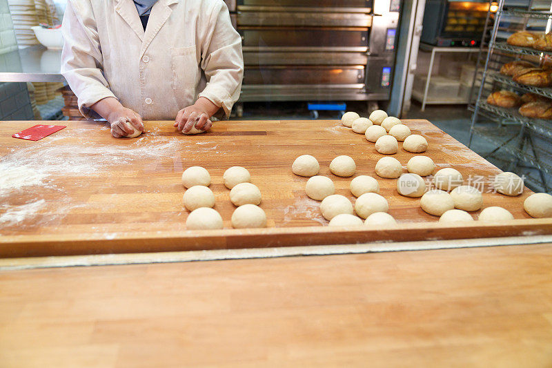 身份不明的面包师在烘焙烤箱中小心翼翼地制作生汉堡面包模具