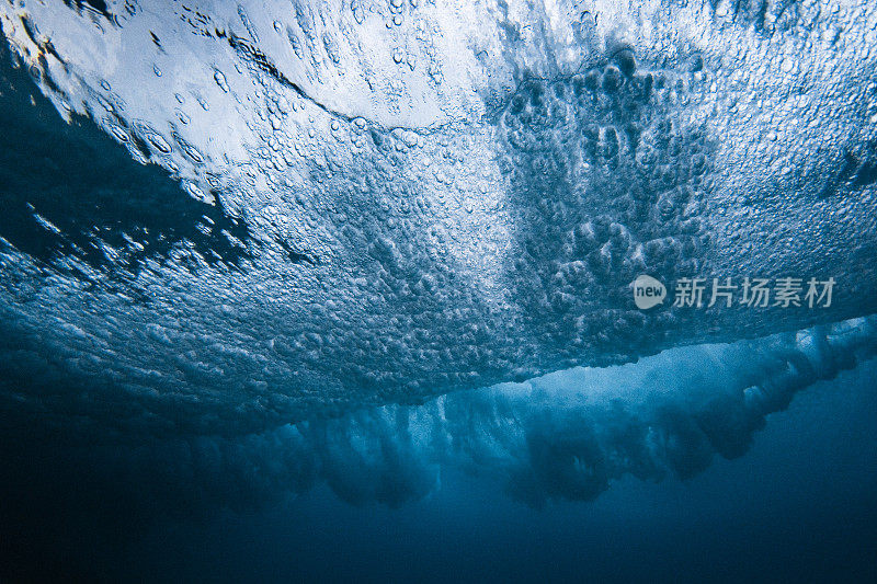 水下照片下的破碎波爆炸与高对比度分散的水模式使用闪光灯