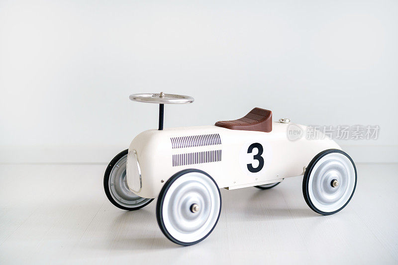 一辆白色的复古玩具车，放在家里的白色乙烯基地板上