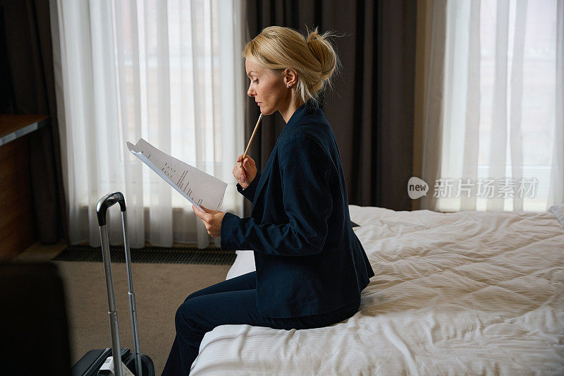 严肃的女商人在酒店卧室里翻看商业文件