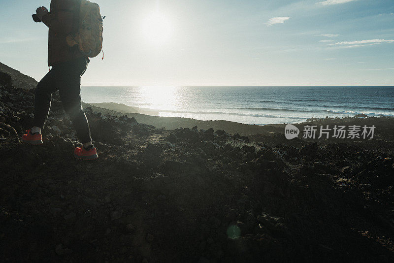 在加那利群岛兰萨罗特岛的火山海岸风景中徒步旅行的妇女