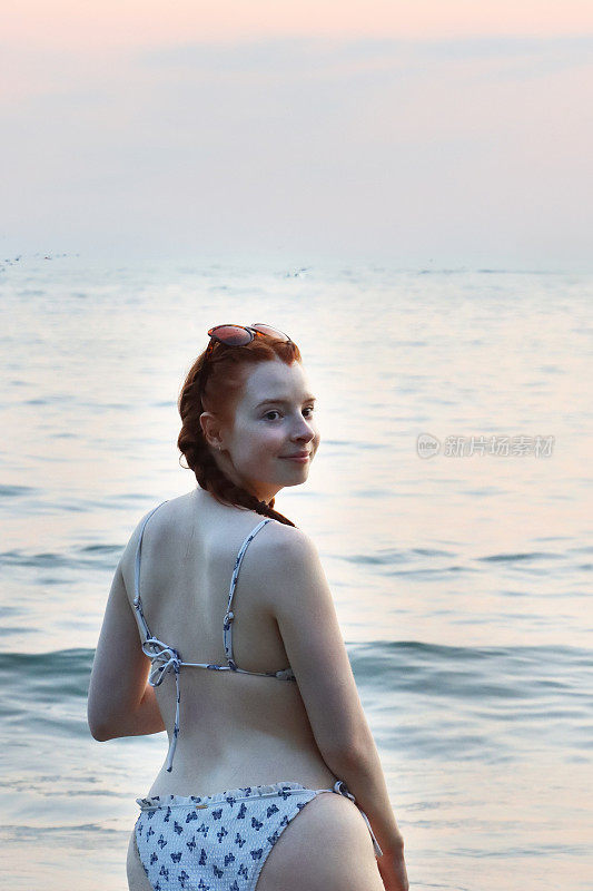 印度果阿冬季度假，帕洛莱姆海滩，穿着两件式泳衣(比基尼)，向后看，后视图，在海滩度假，头上戴着太阳镜，一头红发，扎着辫子的女人走进浅海