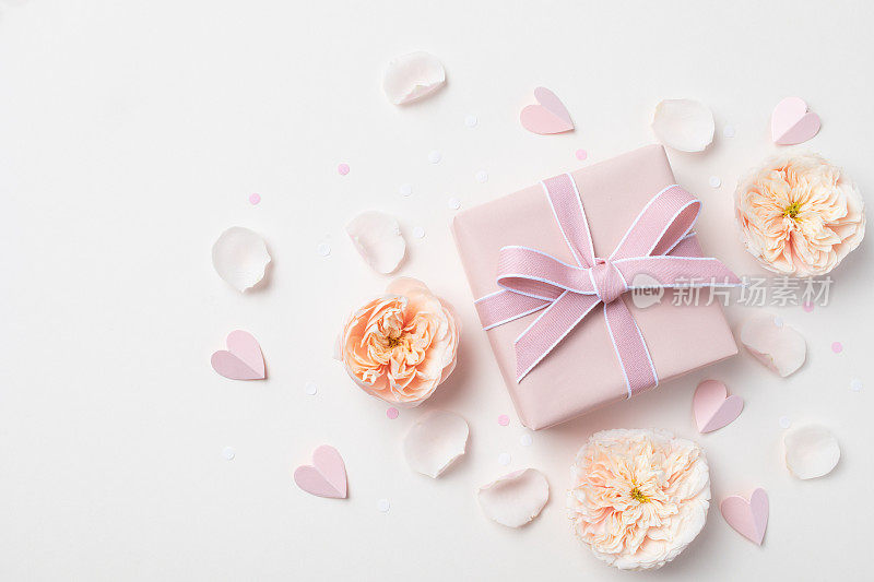 生日，女人或母亲节贺卡。粉红色的心，玫瑰花和礼盒在柔和的桌面视图。