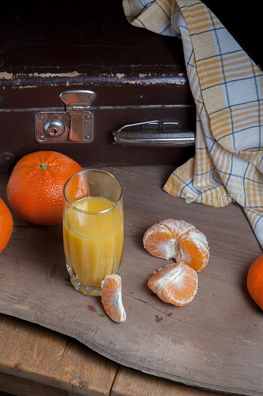 未去皮的圆形成熟橘子或橘子，切片去皮的橘子和一杯新鲜果汁放在木板上