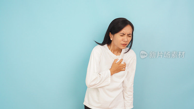 亚洲女性胸痛，痛的表达和手心脏在浅蓝色的背景