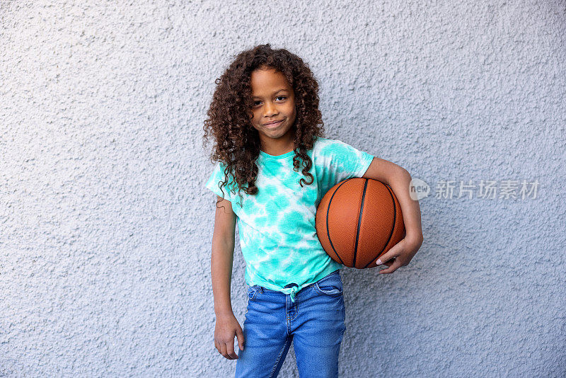 年轻女孩骄傲地站着，拿着一个篮球