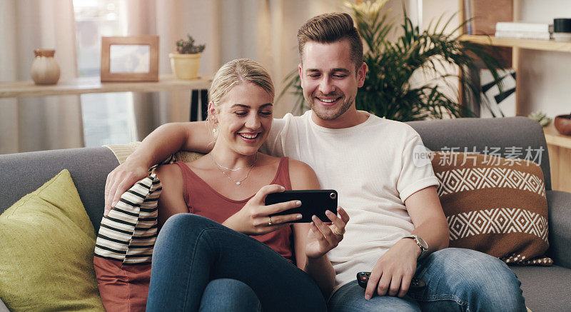 一对年轻夫妇在沙发上用智能手机