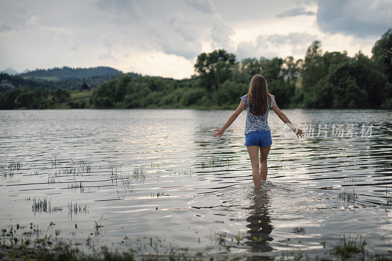 一个十几岁的女孩在湖里散步