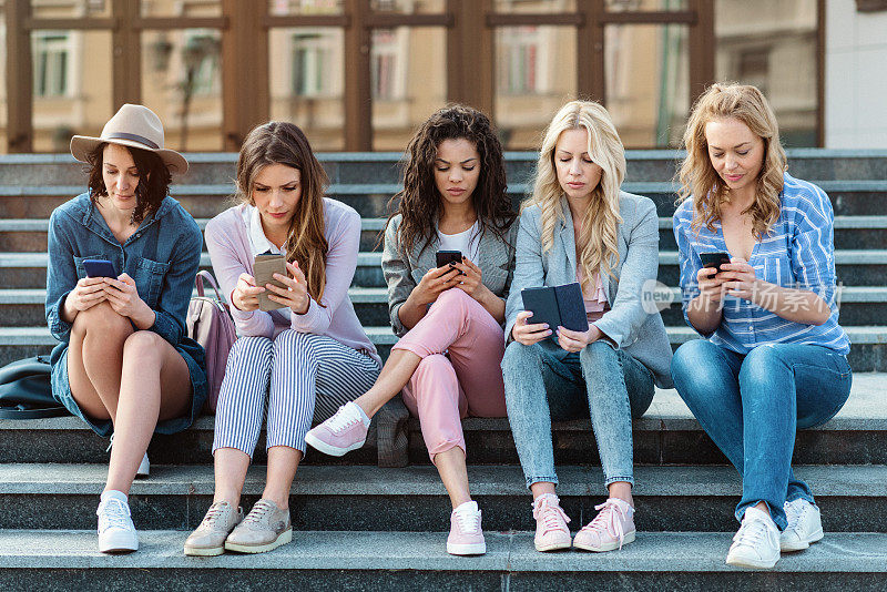 一组五个女人在认真地看手机