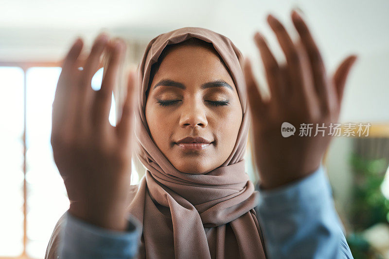 一个年轻的穆斯林妇女在家里的休息室祈祷