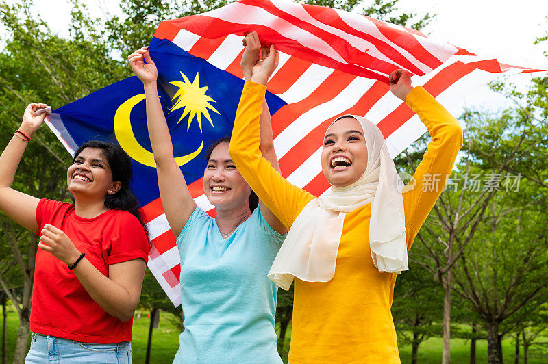 三名来自各个种族的马来西亚青年高举大马国旗，自豪地展示他们的爱国精神和团结精神，庆祝马来西亚国庆日