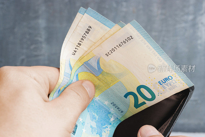 男人从钱包里掏出钱来，20欧元的钞票