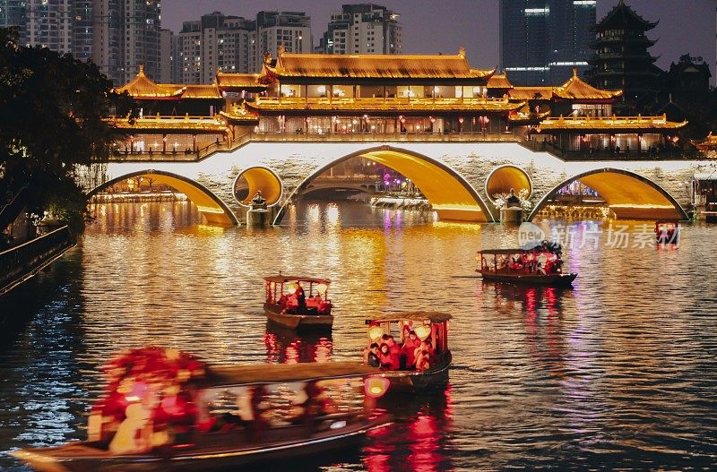 在中国四川成都，夜深人静的小游船在锦江上驶过安顺大桥