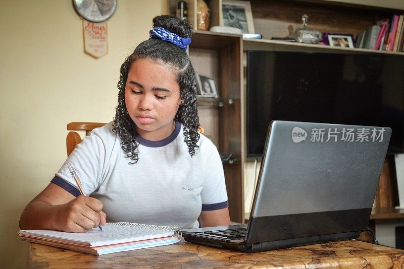 一个十几岁的女孩在家里用笔记本电脑学习