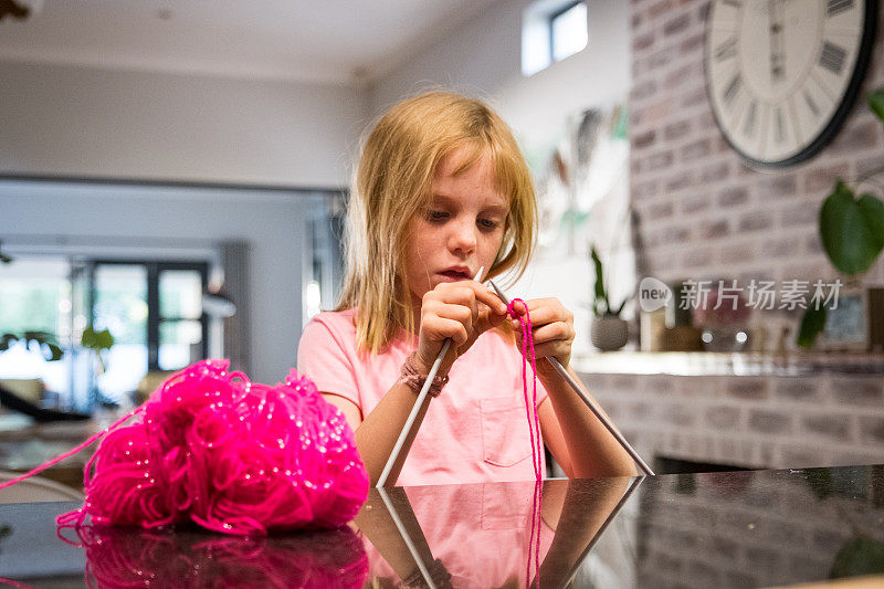 年轻的女孩用粉红色的毛线编织