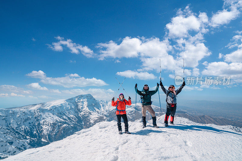成功的登山队伍在冬季，在高海拔雪山峰顶展开登山杆