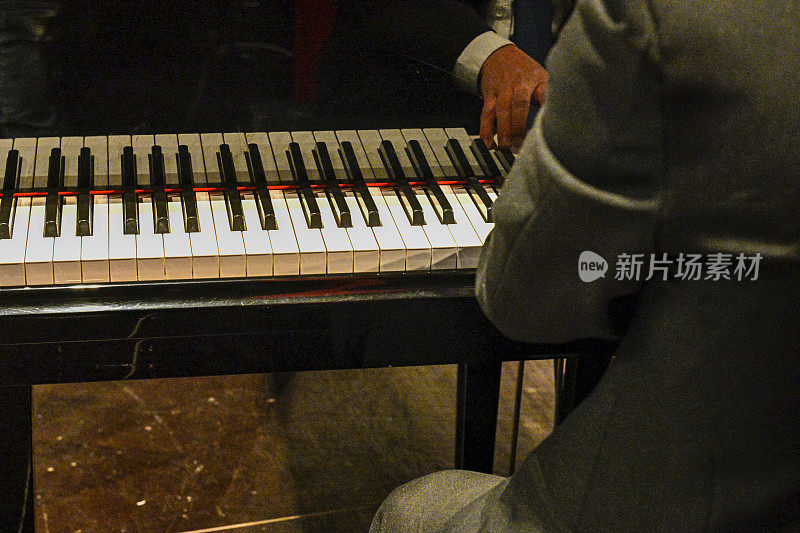 演奏钢琴键盘的音乐会演奏者的手。