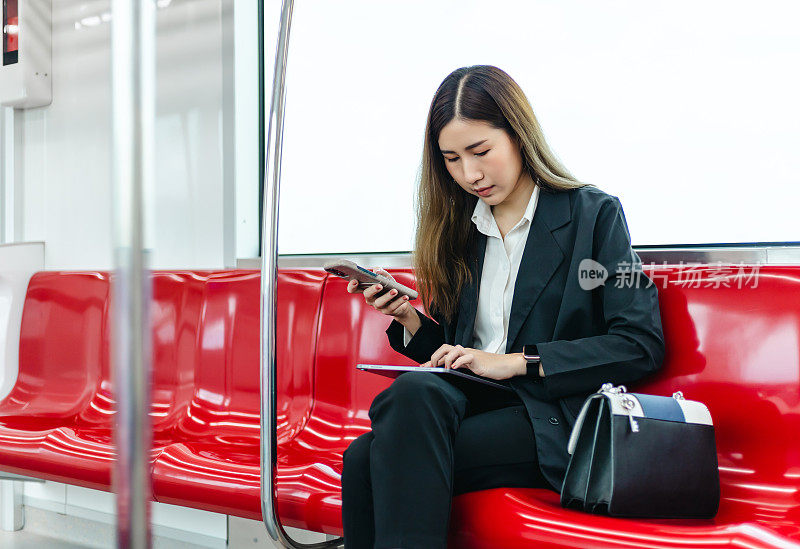 亚洲女商人在去办公室的火车上使用智能手机。
