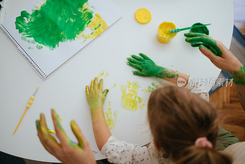 匿名妇女和儿童在家用颜料制作手印