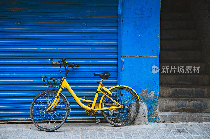 黄色的自行车停在蓝色的墙边