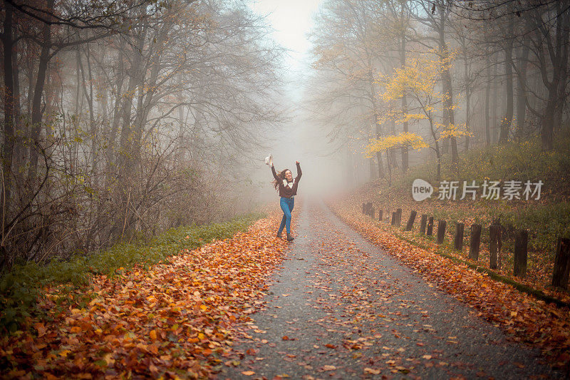 走在雾蒙蒙的秋林路上的女人