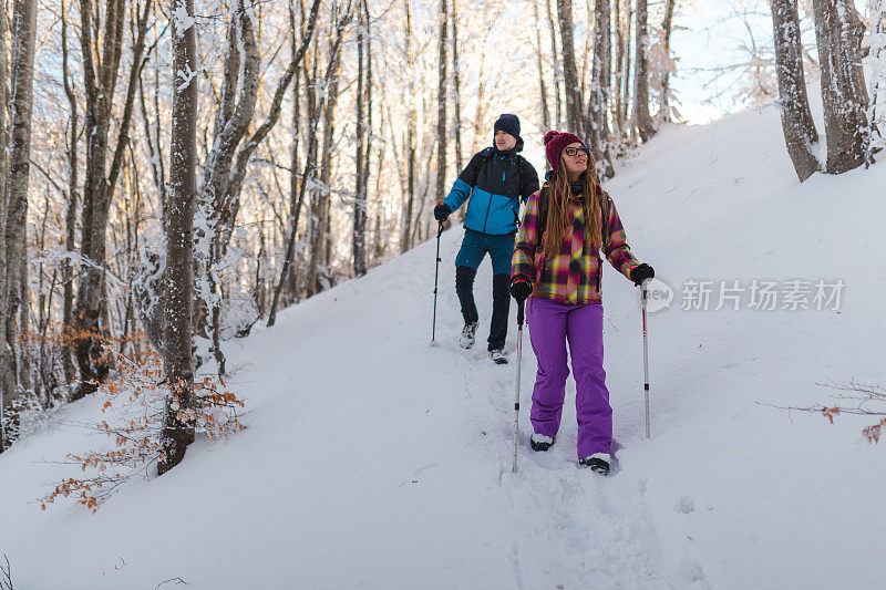 两个年轻的徒步旅行者正从雪山小径上爬下来