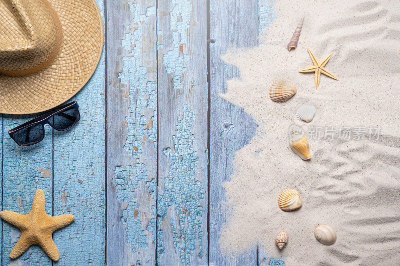 夏天，海滩和度假的概念与自由文本空间。前视图。平面布局以男子草帽、太阳眼镜、大海星、各种海贝和细沙滩为背景的旧蓝色木板