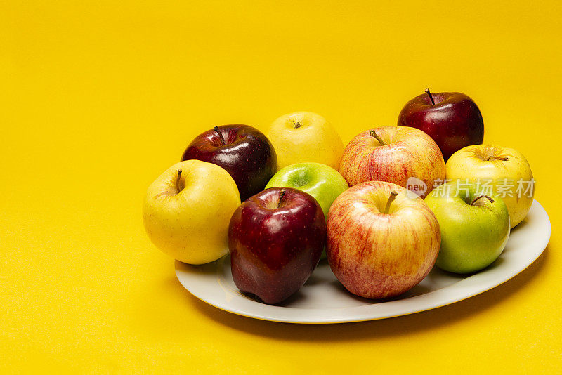 白色盘子上黄色背景上的一组苹果水果